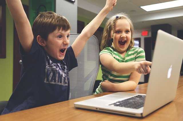 duas crianças comemorando na frente do computador
