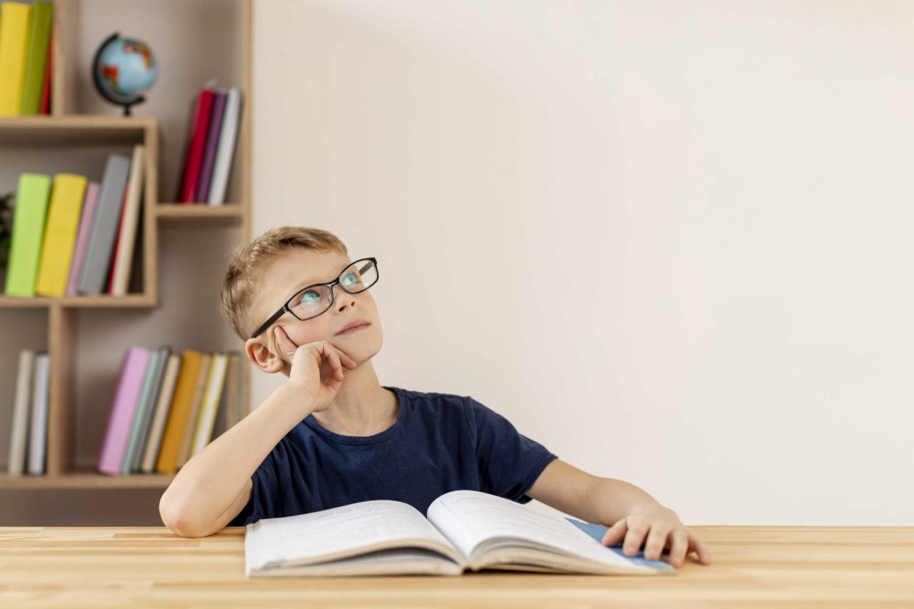 capacidade cognitiva: menino de óculos com livro aberto