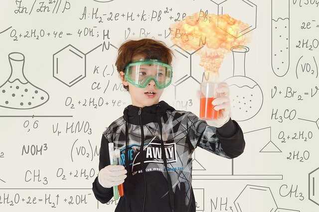 criança atrás de um vidro com muitas fórmulas de quimica